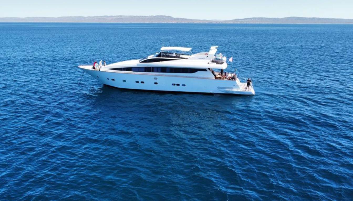 Aerial view of the Sea of Cortez coastline with a luxury yacht cruising past desert mountains and turquoise bays